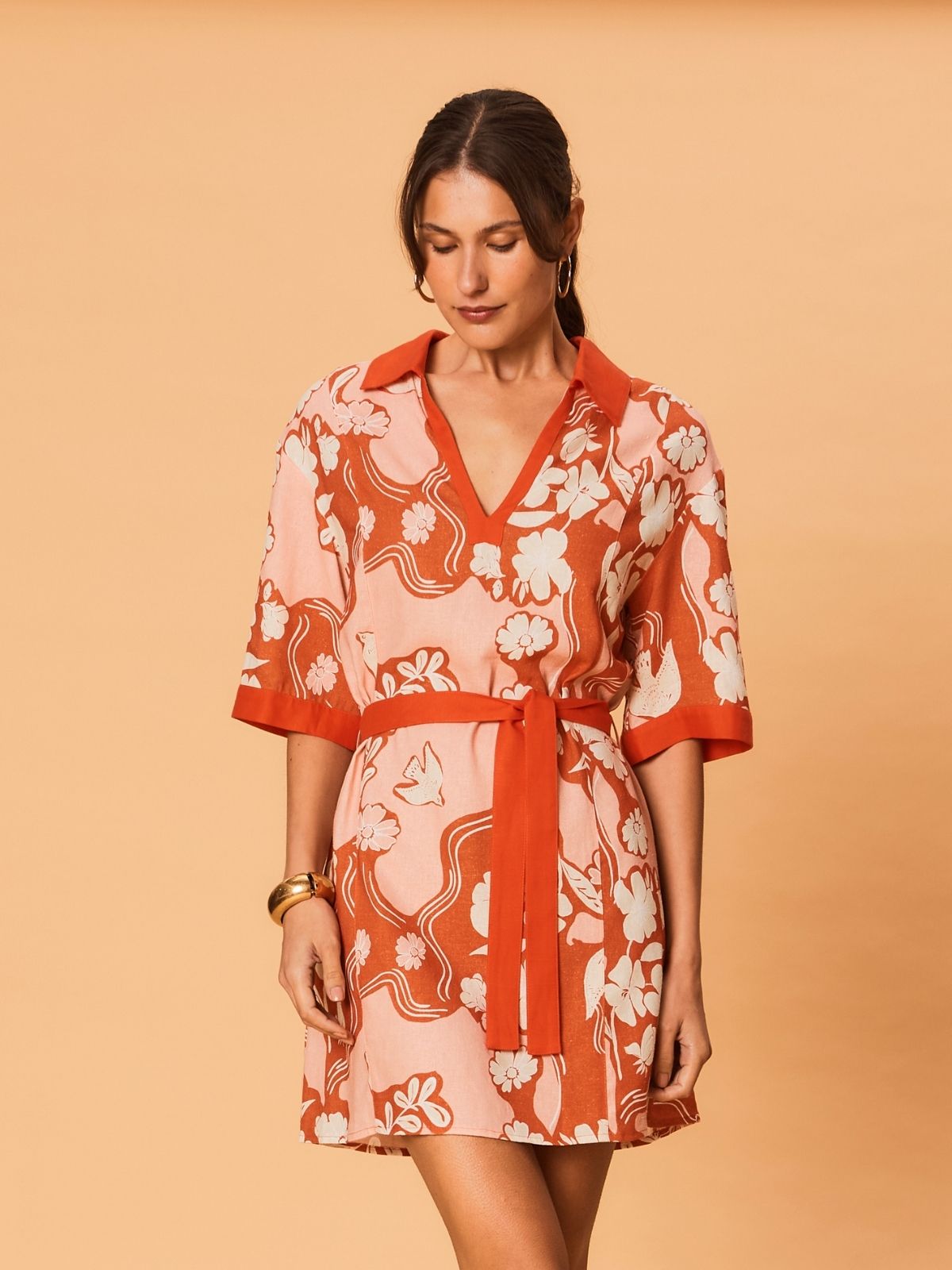 A close-up view of a model wearing the Akira Mini Dress by La Maise Studio, showcasing the Bird Floral print, soft linen-viscose fabric, and collared V-neckline.