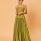 A young woman wearing a green La Maise Verde Clare dress against a beige background.