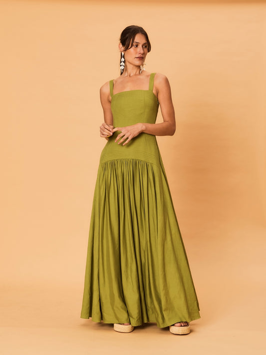 A young woman wearing a green La Maise Verde Clare dress against a beige background.