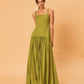 A young woman wearing a green La Maise Verde Clare dress against a beige background.
