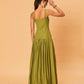 A young woman wearing a green La Maise Verde Clare dress against a beige background.
