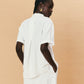 Woman wearing a white outfit against a beige background