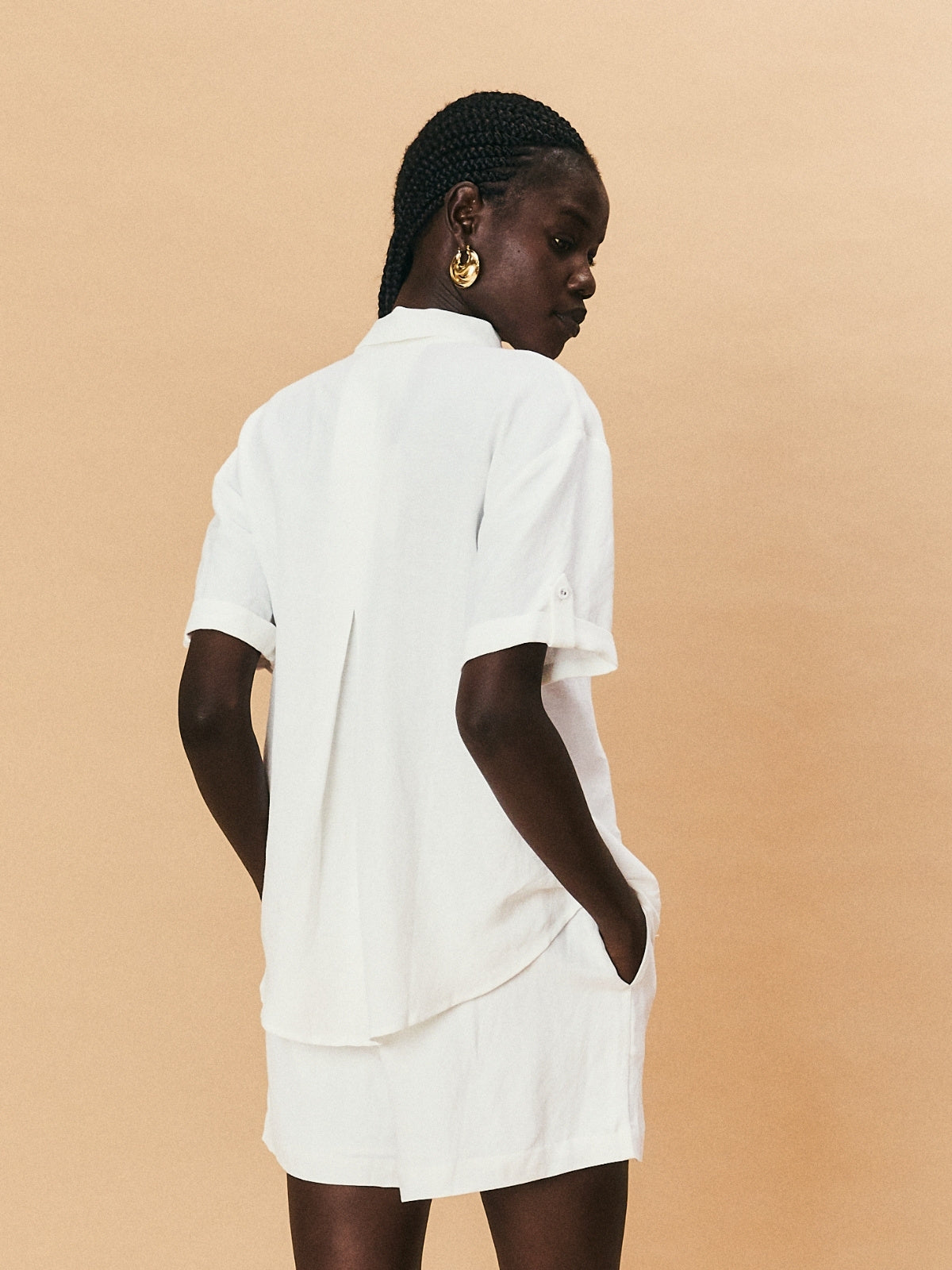 Woman wearing a white outfit against a beige background