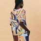 Woman wearing a colorful patterned dress against a beige background