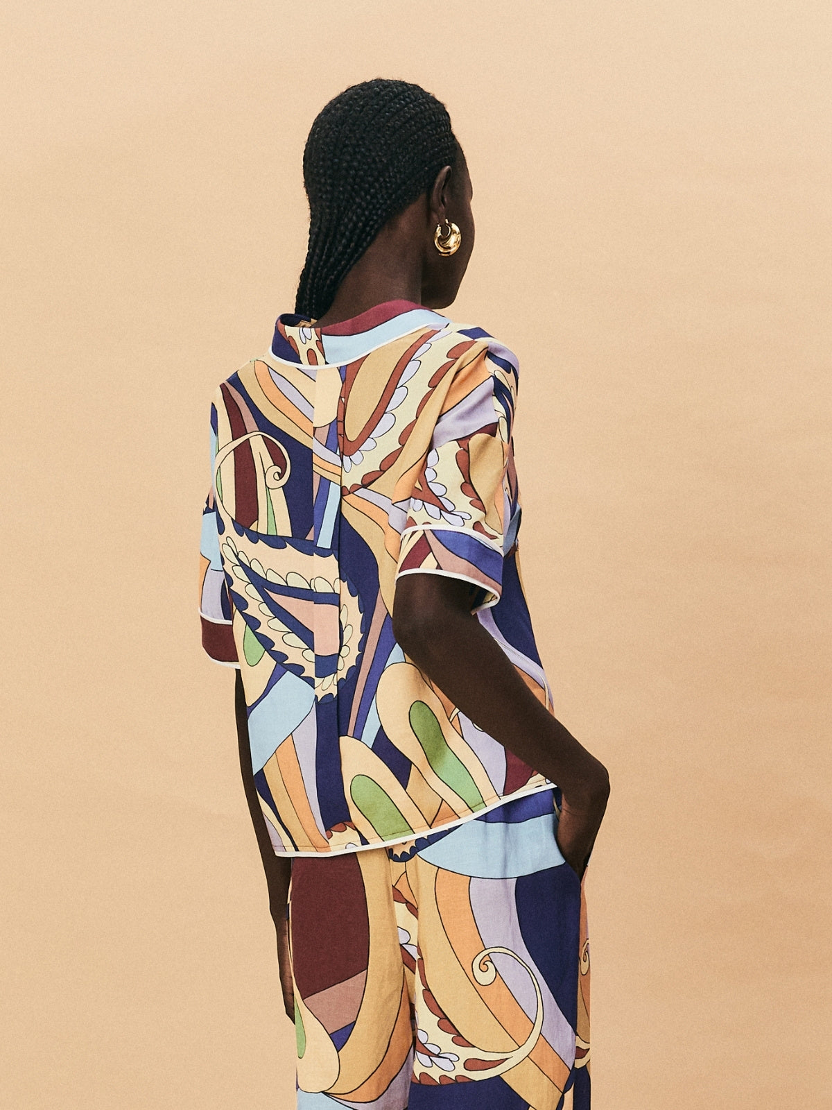 Woman wearing a colorful patterned dress against a beige background