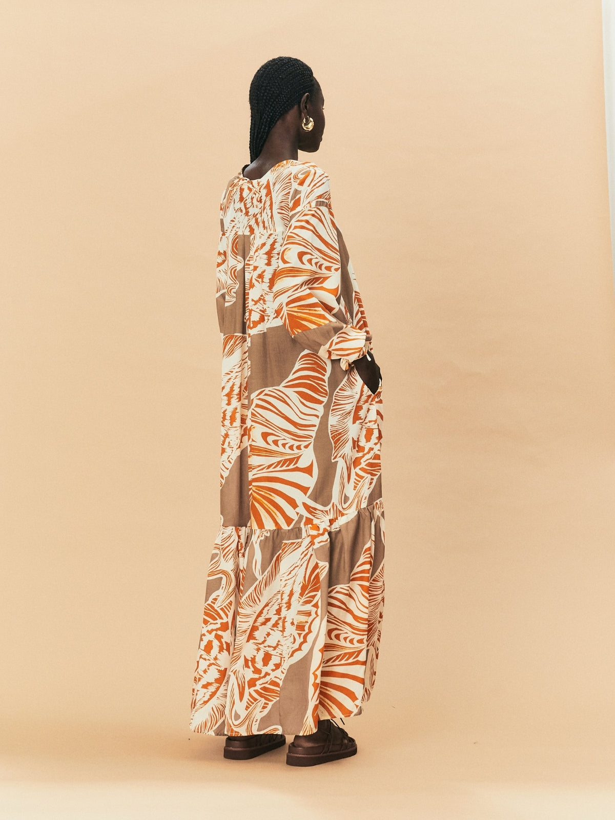 A back view - a woman  wearing La Maise Cannes maxi dress with seashell print.