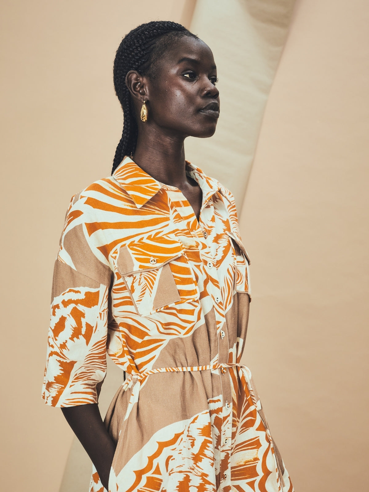 A young woman wearing a La Maise mini dress with seashell print on a beige background.