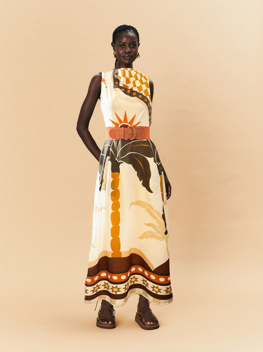 A young woman wearing a patterned La Maise blanc placement dress on a beige background.