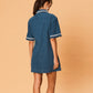 Woman wearing a blue dress with white trim on a beige background