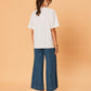 Person wearing a white t-shirt and blue jeans on a beige background
