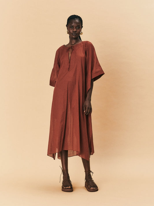 A woman wearing a brown La Maise Lia kaftan dress in brown against a beige background.