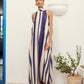 A young woman wearing the Mila Maxi Dress – Stripe by La Maise Studio, featuring a sleeveless high-neck design with vertical navy and cream stripes and a flowing maxi-length silhouette.