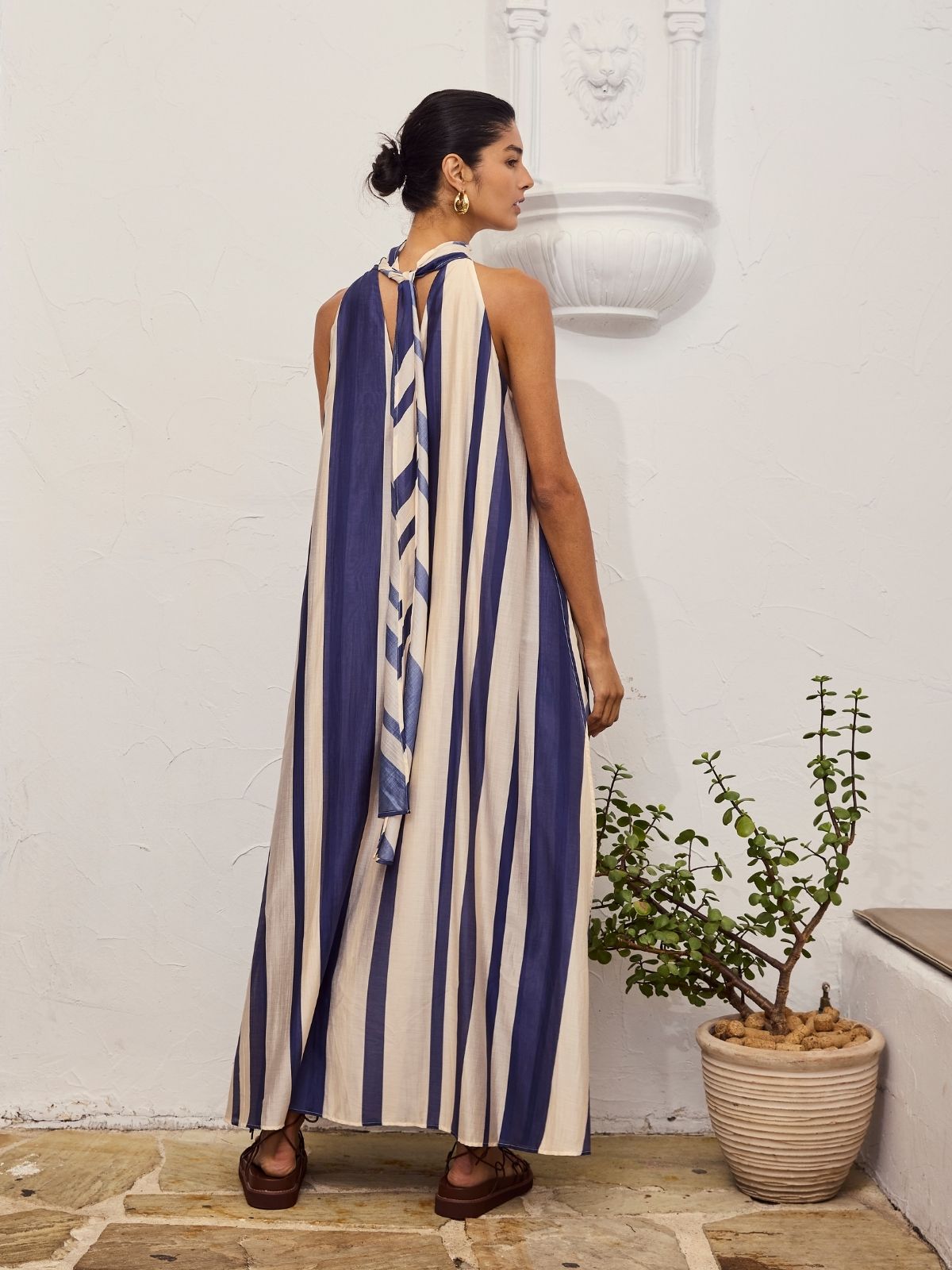 Back view of a model wearing the Mila Maxi Dress – Stripe by La Maise Studio, showing the soft tie detail at the neckline and the relaxed drape of the striped maxi dress.