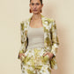 Woman wearing a floral suit with a beige background.