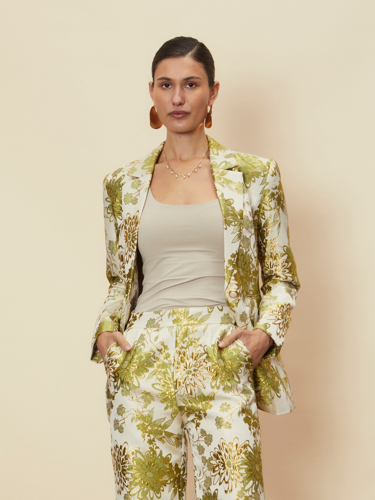 Woman wearing a floral suit with a beige background.