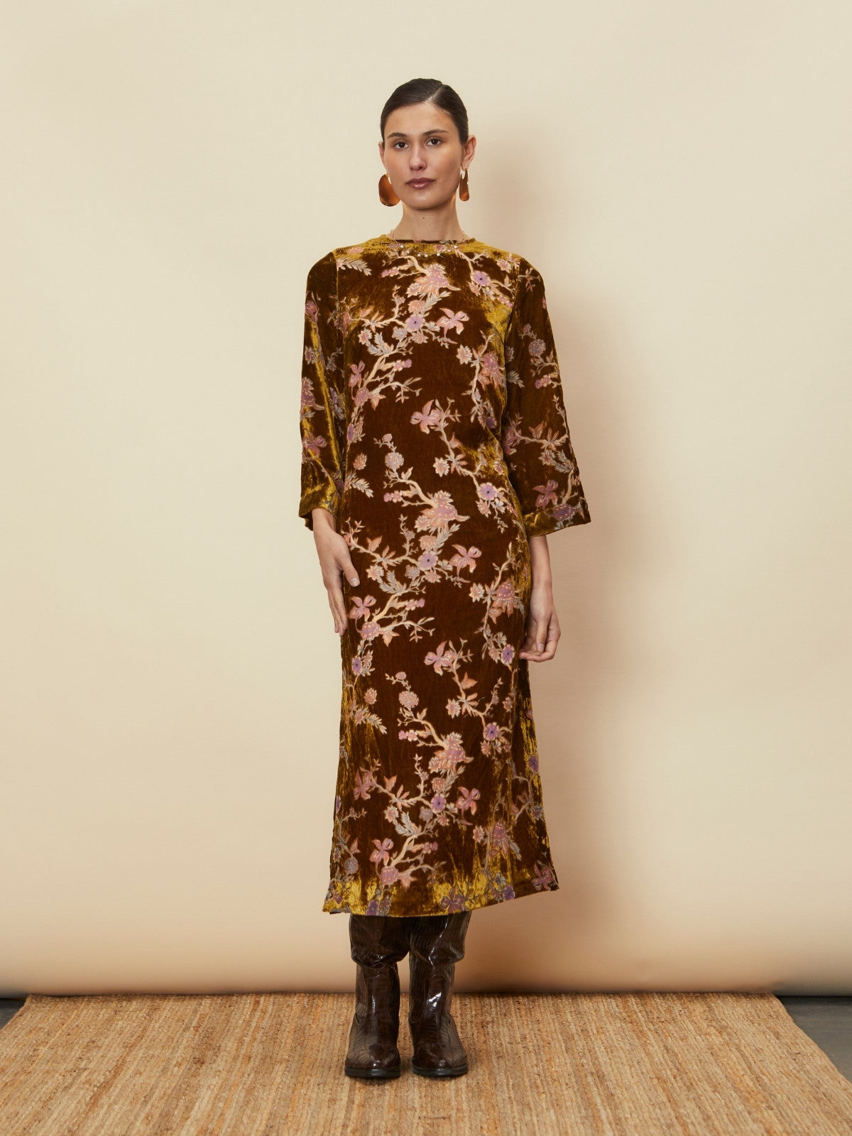 A young woman wearing the Bianca Velvet Midi Dress by La Maise Studio, a brown floral velvet midi dress with three-quarter sleeves and a relaxed silhouette.