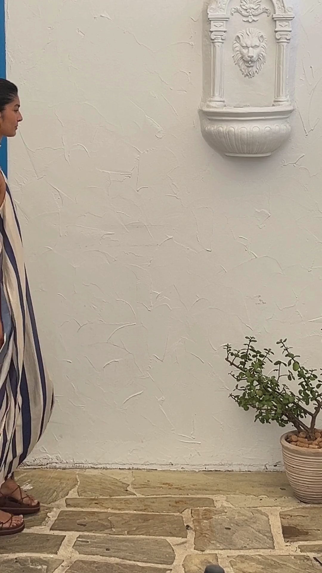 A video showing a young woman wearing the Mila Maxi Dress – Stripe by La Maise Studio, featuring a sleeveless high-neck design with vertical navy and cream stripes and a flowing maxi-length silhouette.